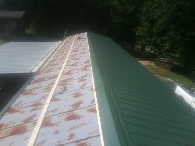 Old rusted panels beside newly installed green metal roofing — Wind Damage Roof Repair by Roofing Brothers in Escalon