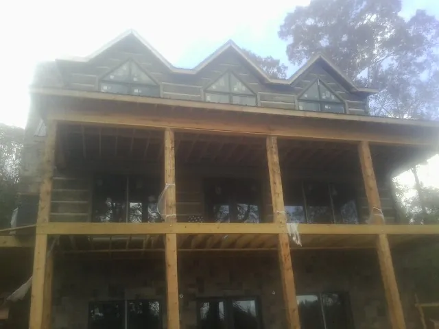 Dormers and porch framing on a large log home under construction — Roof Coating work by our crew in Escalon
