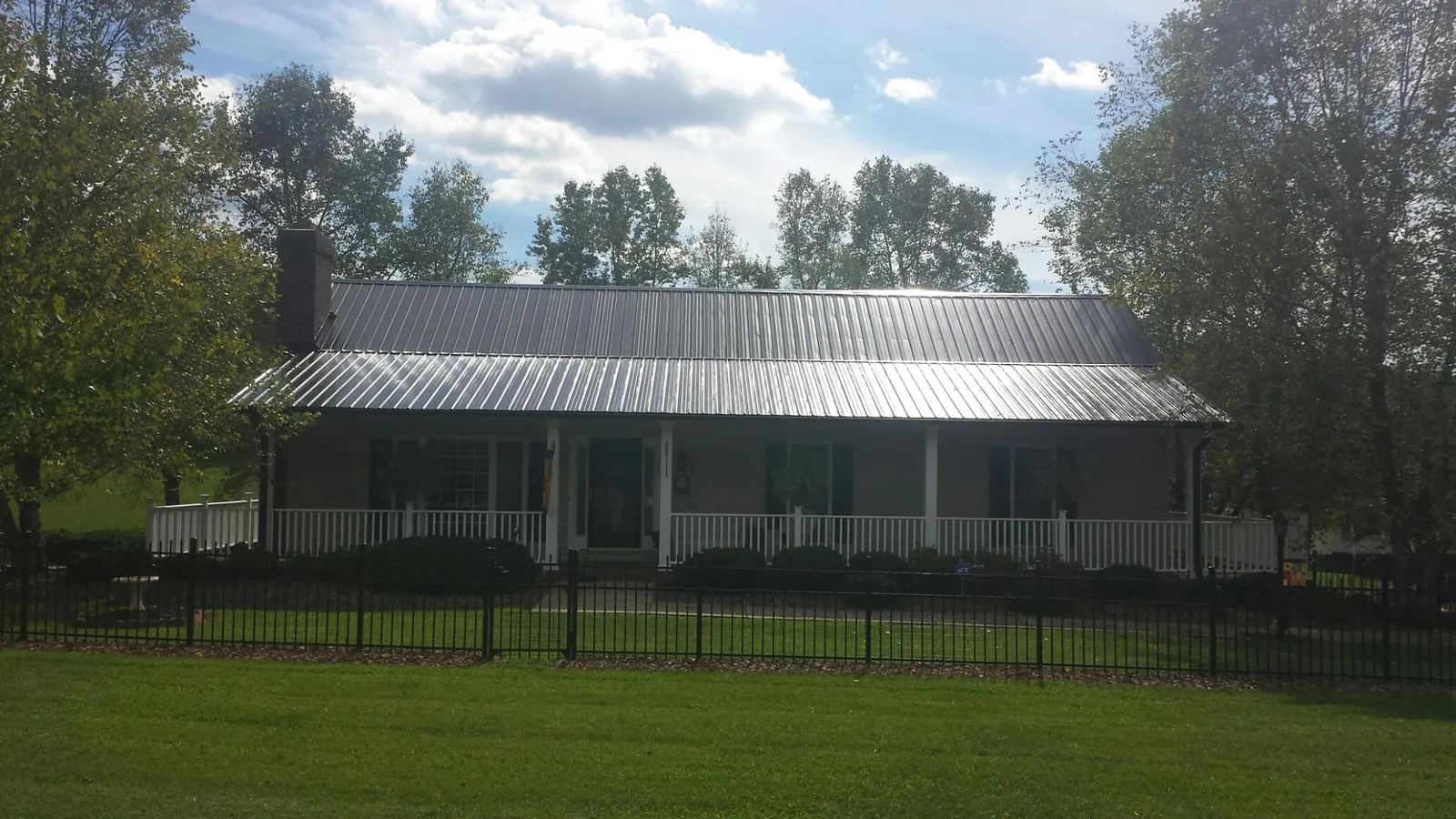 Gray metal roof on a brick ranch with a full width front porch — Gutter Guard Installation work by our crew in Escalon
