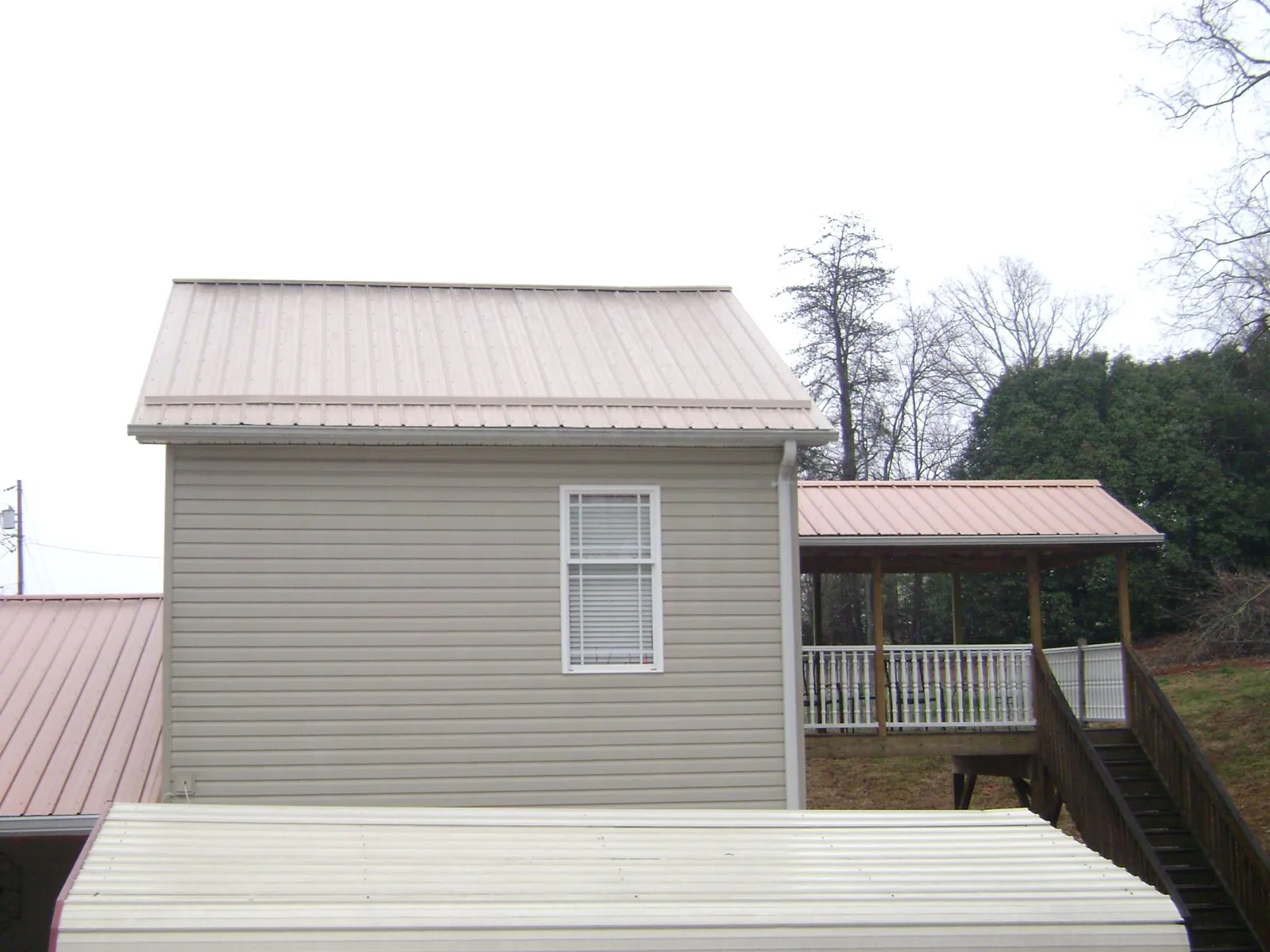 Tan metal roofs on a two story addition and attached porch, from a Roof Replacement job in Escalon