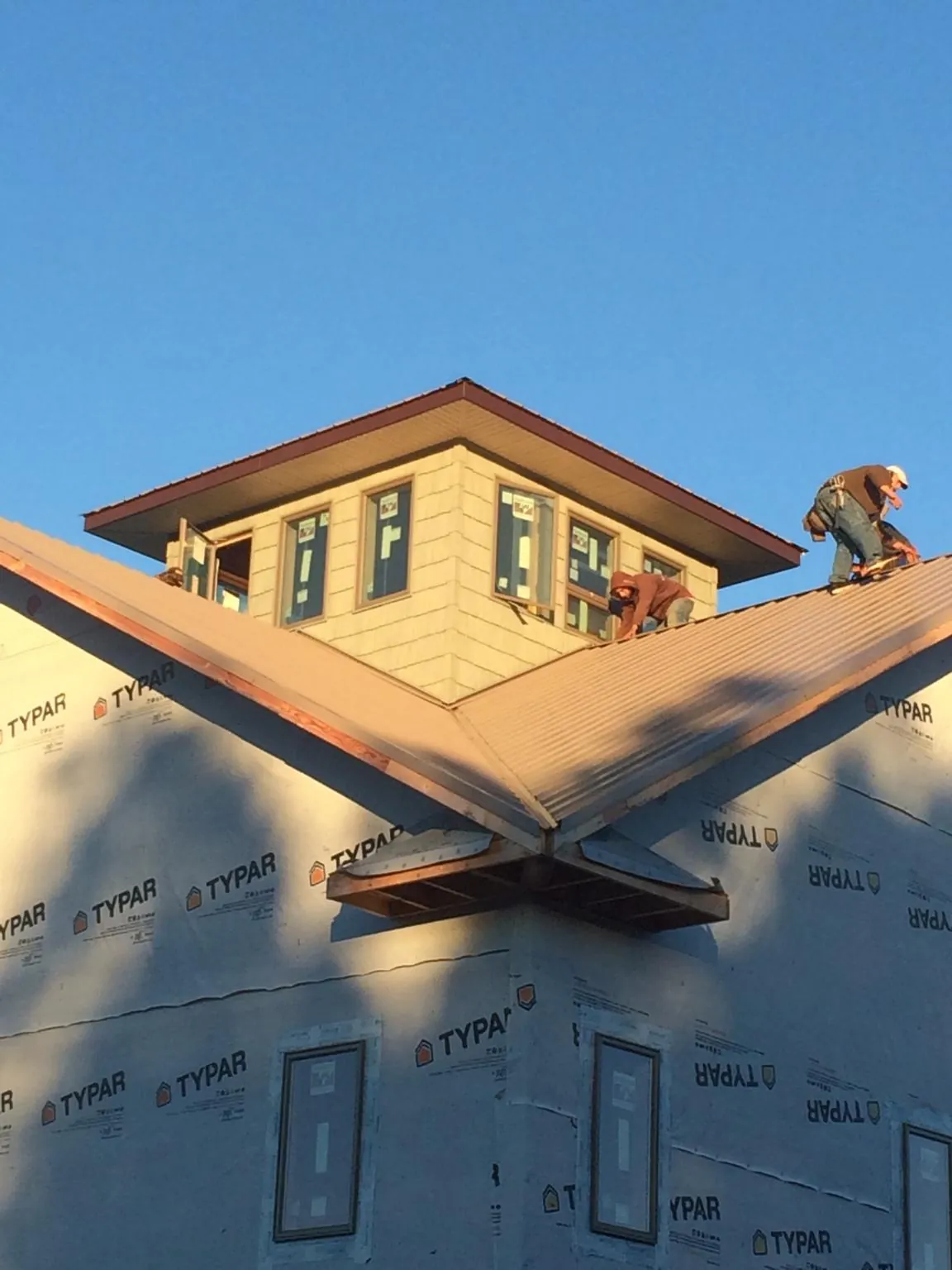 Roofers working around a rooftop cupola on a new metal roof at sunset — Roof Waterproofing in Escalon by Roofing Brothers